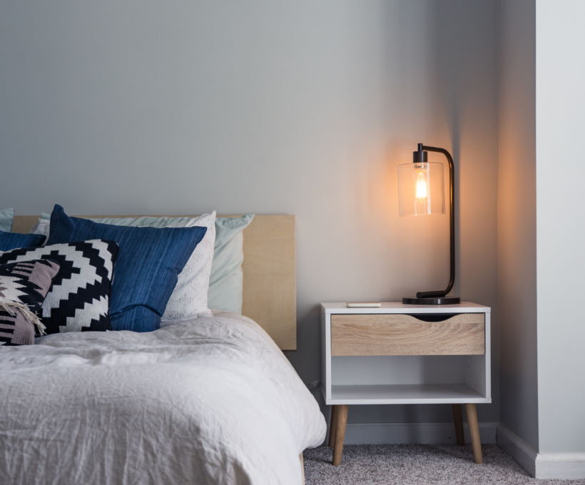 Dormitorio con cama blanca y azul y mesa de noche de madera